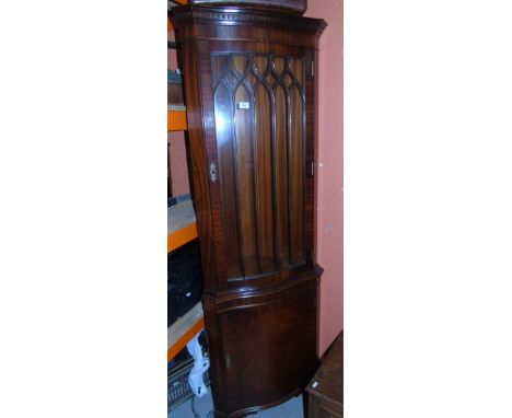 A Mahogany Floor Standing Corner Display Cabinet, having a glazed door above a panel door and standing on bracket feet.