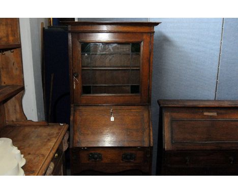 An Arts and Crafts oak bureau display cabinet, with square upper glazed section, above hinged flap writing slope, with banded