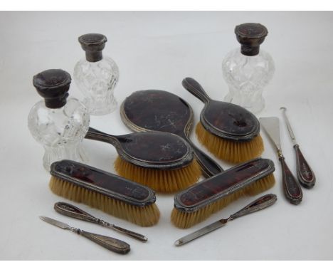 A tortoiseshell and silver mounted dressing table set, including four various brushes, hand mirror, shoehorn, button hook, th