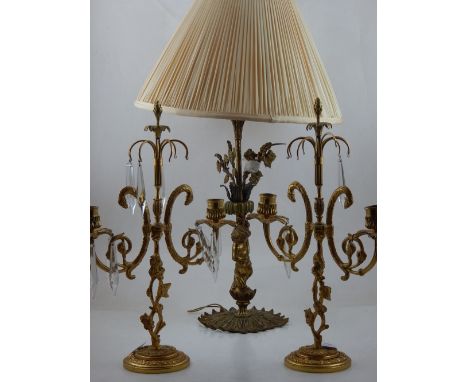 A 20th century gilt table lamp, the base modelled as a cherub, together with pair of gilt two branch candlesticks, (3).