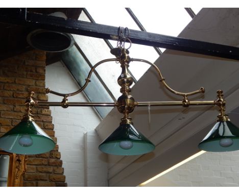 A ceiling mounted brass billiard table lamp, having three green glass shades. L: 110cm H: 55cm W: 25cm