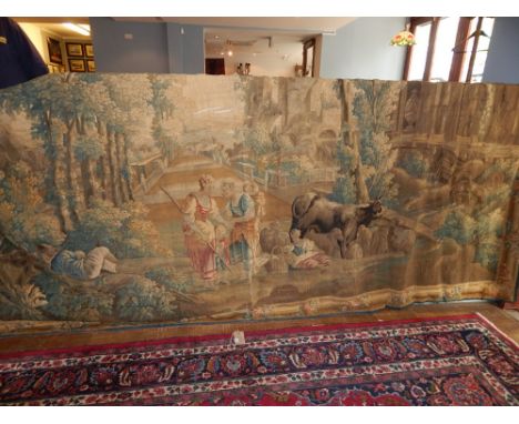 A 19th century Aubusson type polychrome tapestry panel worked with 18th century figures before wooded Abbey ruins within a fl