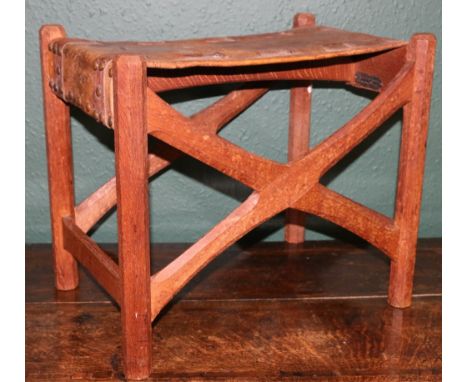 GORDON RUSSELL (1892-1980) an Arts and Crafts oak a leather stool with X frame and chamfered supports, plaque to underside fo