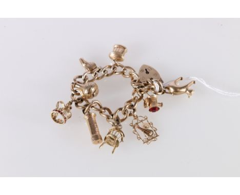 9ct gold curb link charm bracelet with heart shaped padlock closure and nine dependant charms including cat, postbox, moneyba