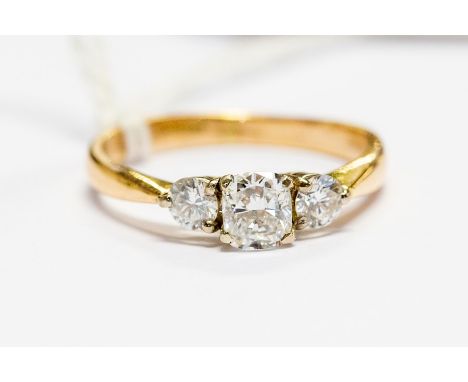 An 18ct gold and diamond three stone ring, with central cushion cut brilliant of 0.56ct flanked by two brilliant cut diamonds