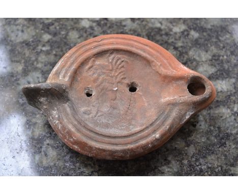  A Roman Terracotta oil lamp with heart shaped nozzle, oval body with series of ovules to the shoulder. The dished centre dec