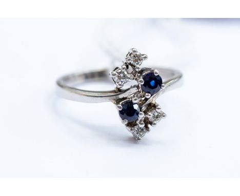 A sapphire and diamond ring, cross over shoulders with round cut sapphire and brilliant cut diamond terminals, 18ct white gol