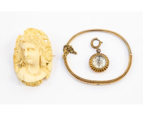 A yellow metal Edwardian bangle with stones, a gilt metal compass charm, a Victorian ivory cameo brooch