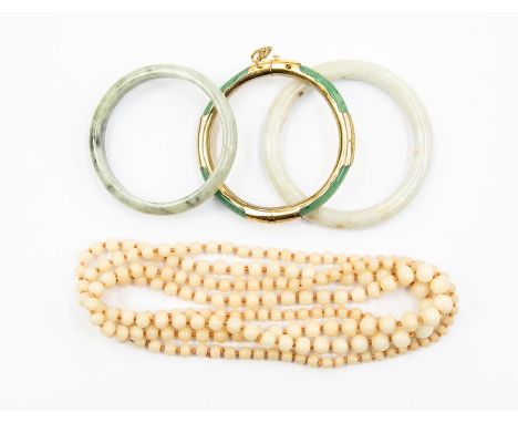 Three jade type bangles comprising white and green versions, one with gilt metal details, along with a bead necklace
