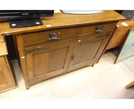 An oak sideboard in the Art Nouveau style on square tapered legs. Two Drawers over double door cupboard.