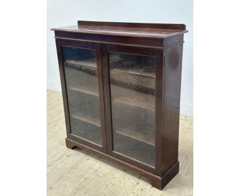 A mahogany upright ledgeback bookcase with moulded edge above two glazed panel doors, enclosing three adjustable shelves, rai