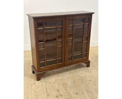 A mahogany bookcase, the rectangular top above a pair of glazed astragal panel doors enclosing three adjustable shelves, rais