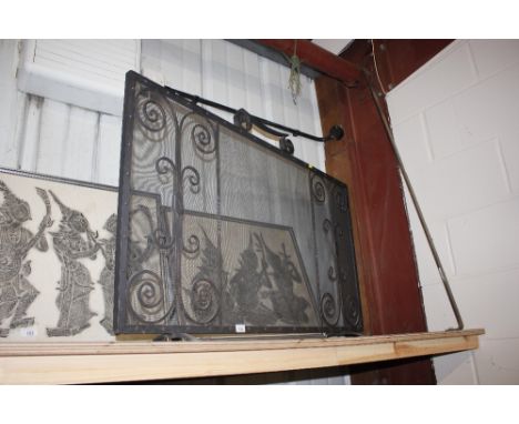A wrought iron and mesh firescreen