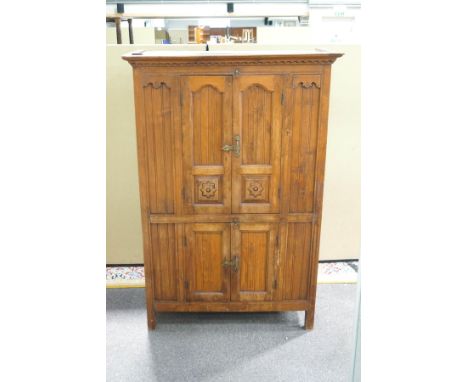 A stained oak panelled cupboard, the upper section with doors enclosing a shelf and two drawers, above a cupboard base, 123cm