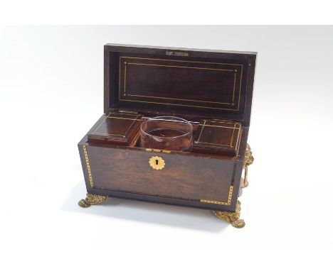 A Regency rosewood tea caddy of sarcophagus form, with lions mask handles, gilt metal feet and brass inlay