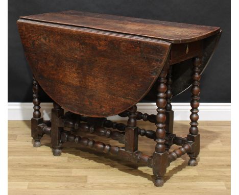 An 18th century oak gateleg dining or breakfast table, oval top with fall leaves, drawer to frieze, bobbin-turned supports an