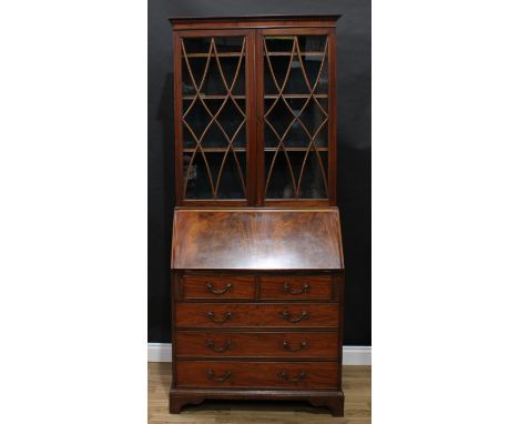 A George III Revival mahogany bureau bookcase, shallow outswept cornice above a pair of glazed doors enclosing three adjustab