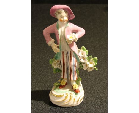 A Derby Patch Mark figure, of a boy, holding a flower posy, wearing a pink hat and waistcoat, striped trousers, 12.5cm high, 