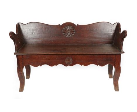 A Joined Oak Bench, late 18th/early 19th century, the low back support centred by a carved flowerhead, with scrolled arms abo