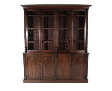 A Late Victorian Oak Library Bookcase, circa 1900, the bold cornice above four metal grille doors, all between guilloche carv