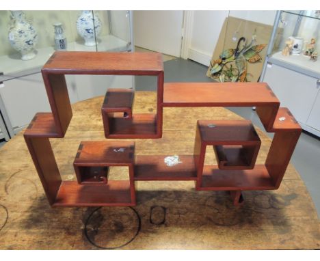 An Oriental hardwood display shelf of scroll form by George Zee & Co., Hong Kong, L. 61cm.