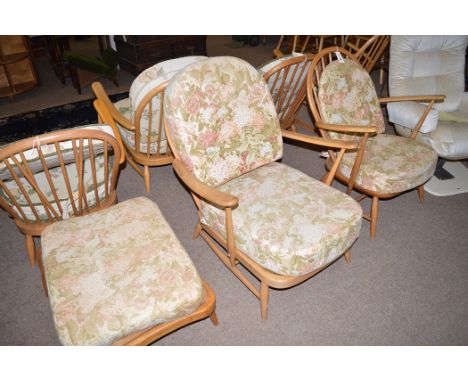 An Ercol covered seat open arm easy chair with loose seat and back cushions; a larger similar Ercol chair and a matching foot