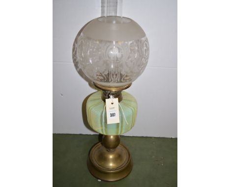 A late 19th Century table oil lamp, frosted and clear glass globular shade above a cranberry glass reservoir, and raised on b