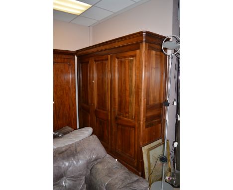 A Willis and Gambier style wardrobe, the flared cornice above three panelled doors enclosing hanging space and top shelf, rai