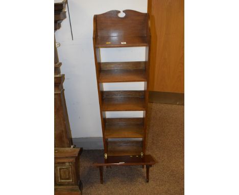 A tall narrow open bookcase and a mahogany shelf.