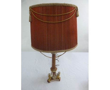 A porcelain red ground and gilded table lamp on triform base with applied sphinx to the corners