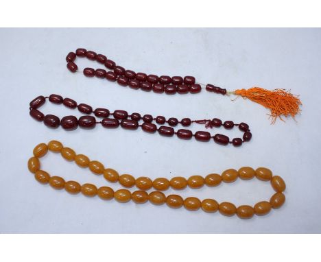 A reconstituted light amber oval bead necklace together with two dark simulated amber necklaces
