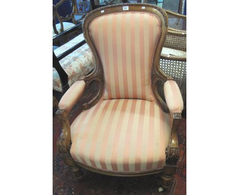 Walnut upholstered fireside open armchair with padded arms on turned legs and ceramic casters.(B.P. 24% incl. VAT)