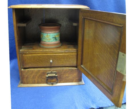 Oak smoker's cabinet with single inlaid panel door revealing fitted interior with drawers and ceramic tobacco jar. (B.P. 24% 