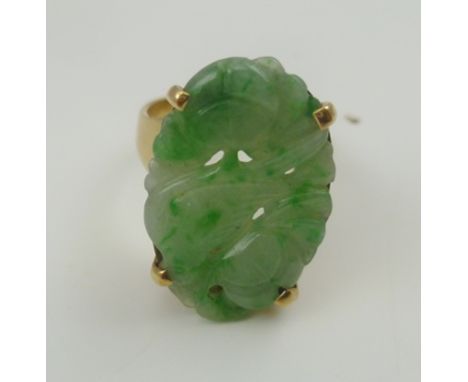 A 9CT GOLD DRESS RING inset carved Jade oval stone, carved with a bird amidst flowers 