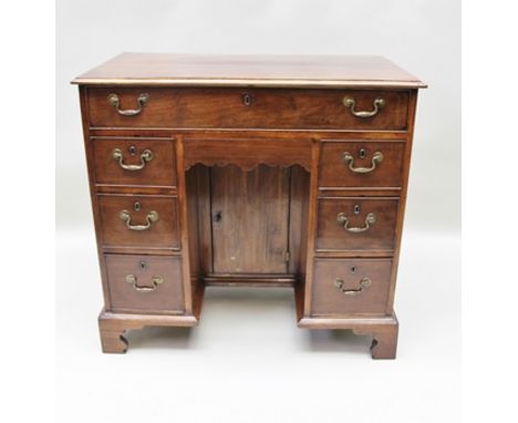 A GEORGE III MAHOGANY DESK fitted one long drawer, pedestals of small drawers, with brass handles about a central recessed cu