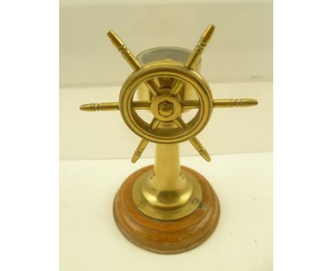 A BRASS MODEL OF A SHIP'S WHEEL inset with a compass, on polished wood base, 13cm high 