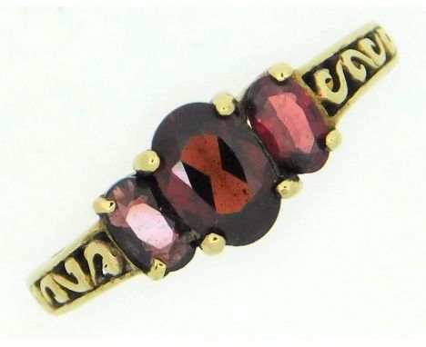 A 9ct gold ring with carved decor to the shank, set with three garnets, 2.3g, size O