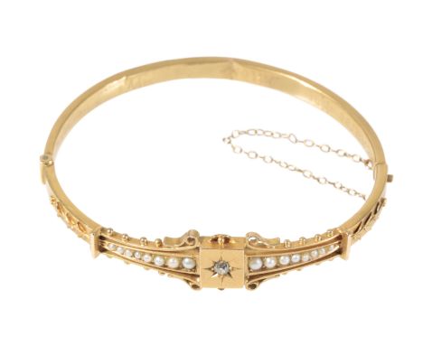 A VICTORIAN GOLD, DIAMOND AND SEED PEARL HINGED BANGLE with attached safety chain, stamped "15K", (c.8.1 grams total weight)