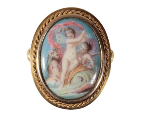 AN OVAL GOLD AND PORCELAIN PANEL CHERUB RING the oval-cut porcelain decorated with cherubs, within a gold rope-twist border, 