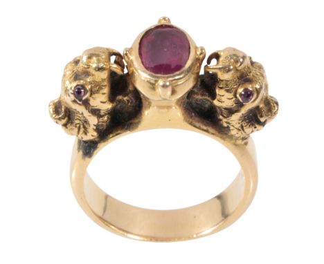 A RUBY DRESS RING the oval-cut ruby, (unable to test), closed back, flanked to either side with a dog's head, set with ruby e