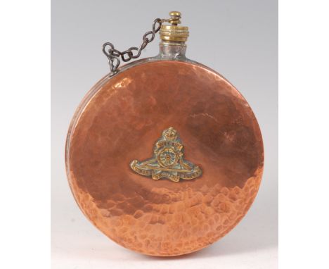 An early 20th century hammered copper flask of circular form, having a brass screw cap and applied Royal Artillery crest, dia