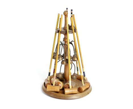 A TABLE CROQUET SET EARLY 20TH CENTURY with a wooden stand supporting eight mallets, four balls, two marker posts and eight h