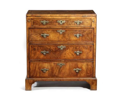 A GEORGE II WALNUT BACHELOR'S CHEST C.1725-30 with cross and feather banding, the hinged fold-over top with a burr veneered p