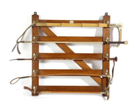 AN OAK WHIP RACK BY MAXWELL, FIRST HALF 20TH CENTURY in the form of a five-bar gate, with brass hooks, with an ivorine trade 