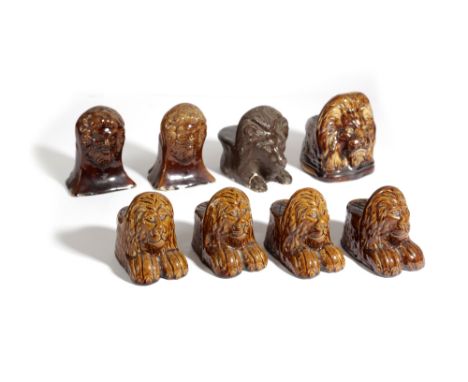 EIGHT POTTERY LION SASH WINDOW / FURNITURE RESTS; 19TH CENTURY; seven with a treacle glaze, comprising: a set of three, one v