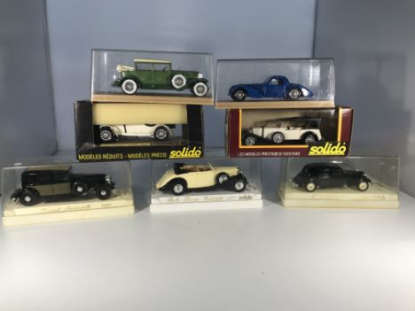 Seven Solido model cars in cases. A Cadillac 452 A, a Bugatti Atalante, a Mercedes SSKL, a Mercedes SS, a Renault Reinastella