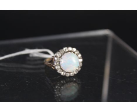 A lovely opal and diamond ring, the centre circular opal framed by eighteen old cut diamonds mounted in silver with pierced s