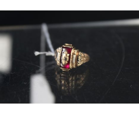 A 10K college style ring set with red stone, black enamel to shoulders with date 1953, size M