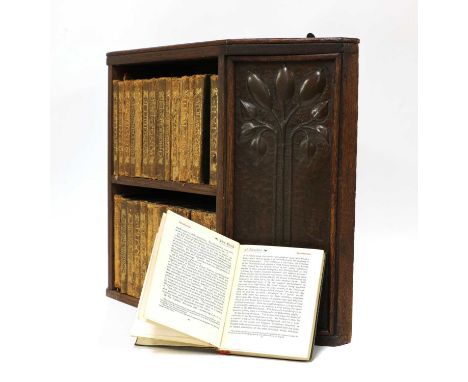 An Arts and Crafts oak hanging bookshelf,centred with a shelf and flanked with embossed panels of fruiting trees, 48.5cm wide