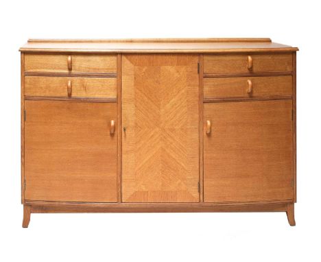 A Cotswold School oak bow-front sideboard,centred with a quarter veneered cupboard, flanked each side with two drawers, one w